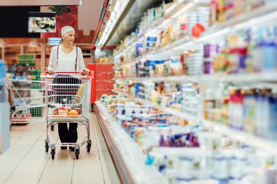 Kundin mit Einkaufswagen im Supermarkt: Wenn Produktionskosten für Lebensmittel steigen, können Preisanpassungen notwendig sein.