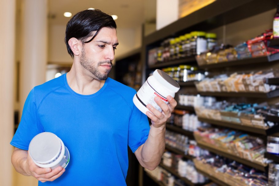 Ein Mann prüft das Etikett einer Dose in einem Sportshop: Nahrungsergänzungsmittel können helfen, den erhöhten Nährstoffbedarf beim Sport zu decken.
