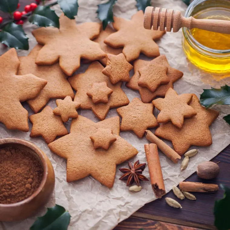 Braune Lebkuchensterne mit Zimtstangen sowie Honig und Gewürz in Schälchen