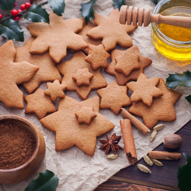 Braune Lebkuchensterne mit Zimtstangen sowie Honig und Gewürz in Schälchen