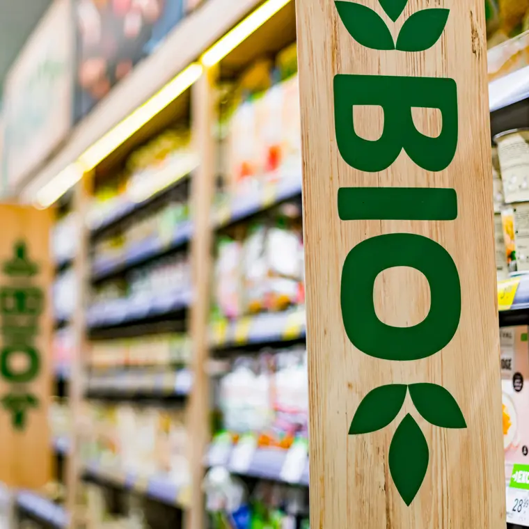 Supermarktregal mit großem Holzschild, auf dem der Schriftzug „Bio“ aufgedruckt ist.