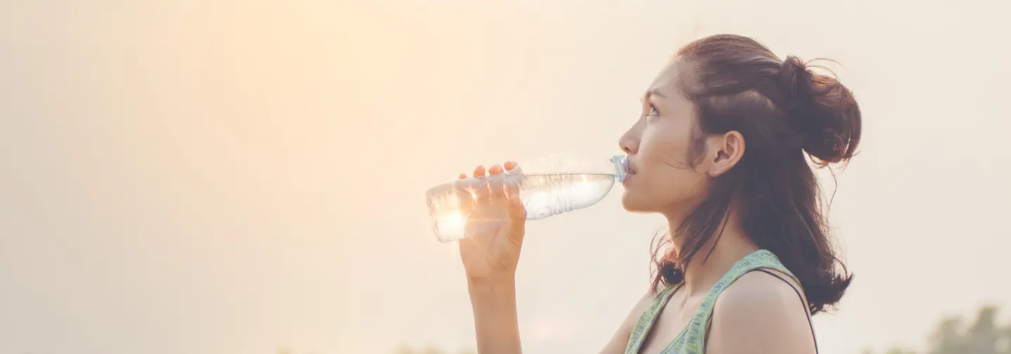 Eine Frau trinkt Mineralwasser und nimmt Mineralstoffe und Spurenelemente zu sich.