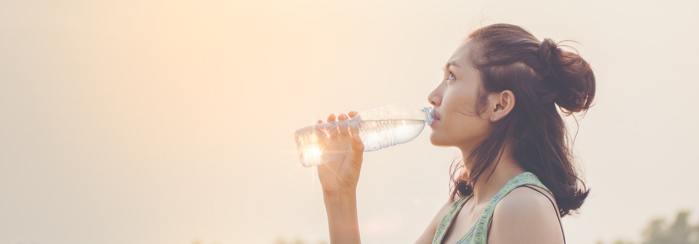 Eine Frau trinkt Mineralwasser und nimmt Mineralstoffe und Spurenelemente zu sich.