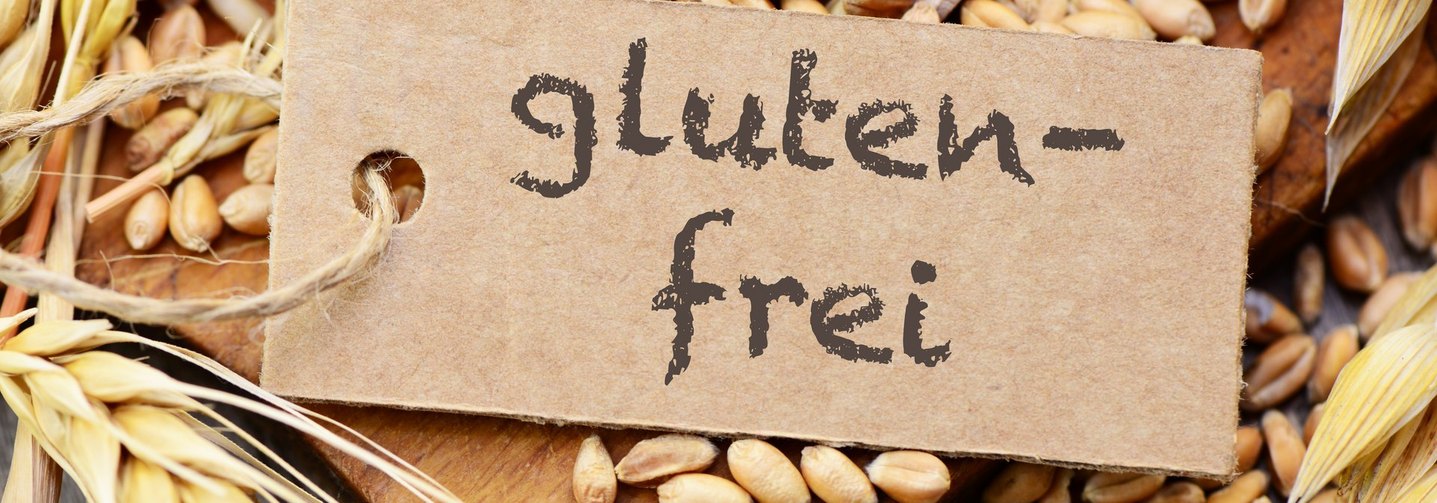 Das Bild zeigt einen Kartonanhänger mit dem Schriftzug „glutenfrei” vor Getreidekörnern.