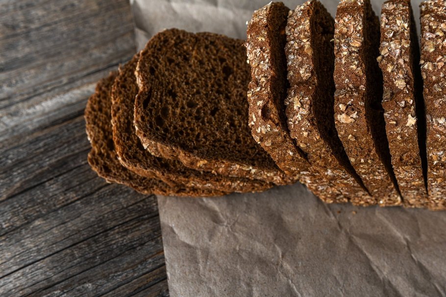 Brotscheiben auf einem Tisch: Das vorgeschnittene Vollkornbrot aus dem Supermarkt ist laut NOVA-Klassifikation „hochverarbeitet“, nicht aber das Croissant vom Bäcker ums Eck. Foto: TanyaRozhnovskaya / iStock