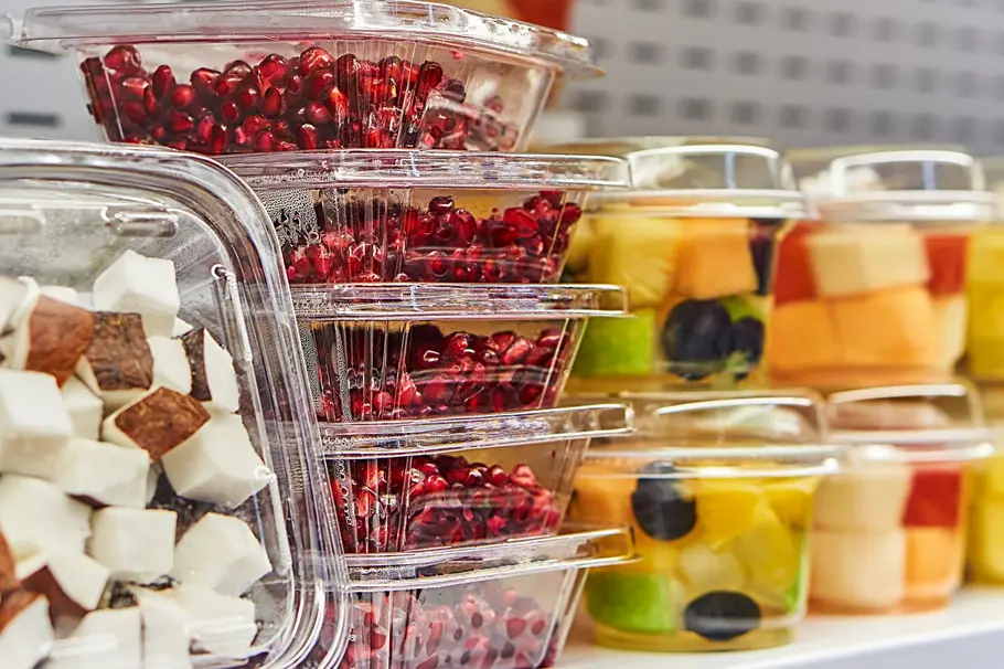 Verschiedene Früchte – wie Beeren oder Kokosnussstücke – in Kunststoffverpackungen im Supermarkt