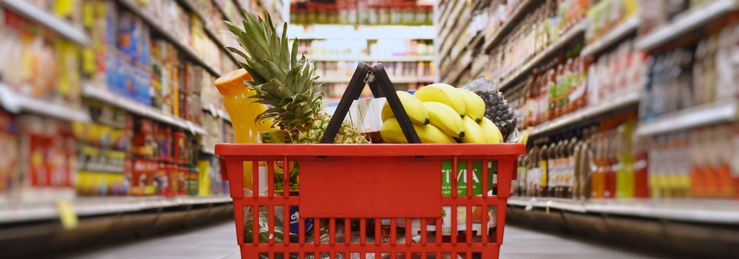 Korb mit Lebensmitteleinkauf auf dem Boden im Supermarkt: Die Lebensmittelpreise für Verbraucherinnen und Verbraucher legt der Handel fest.