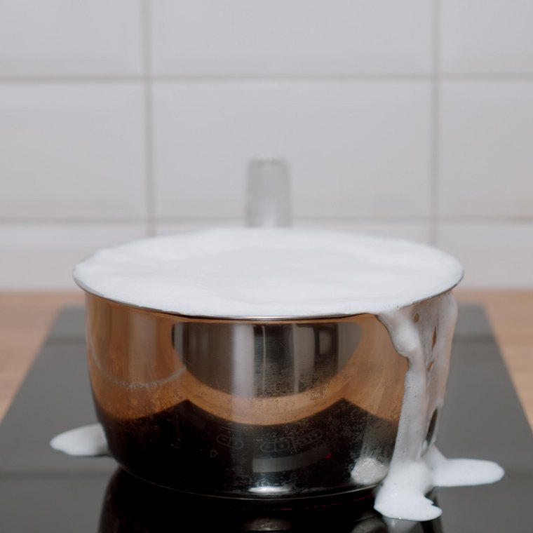 Topf mit überkochender Milch auf dem Herd