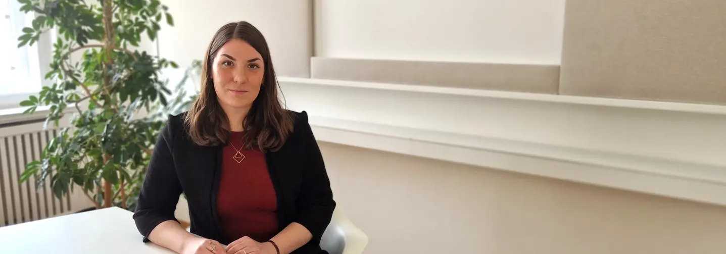 Tamara Rudavsky, Referentin für Lebensmittel- und Futtermittelrecht beim Fachverband der Lebensmittelindustrie, sitzt an einem Tisch und blickt in die Kamera.