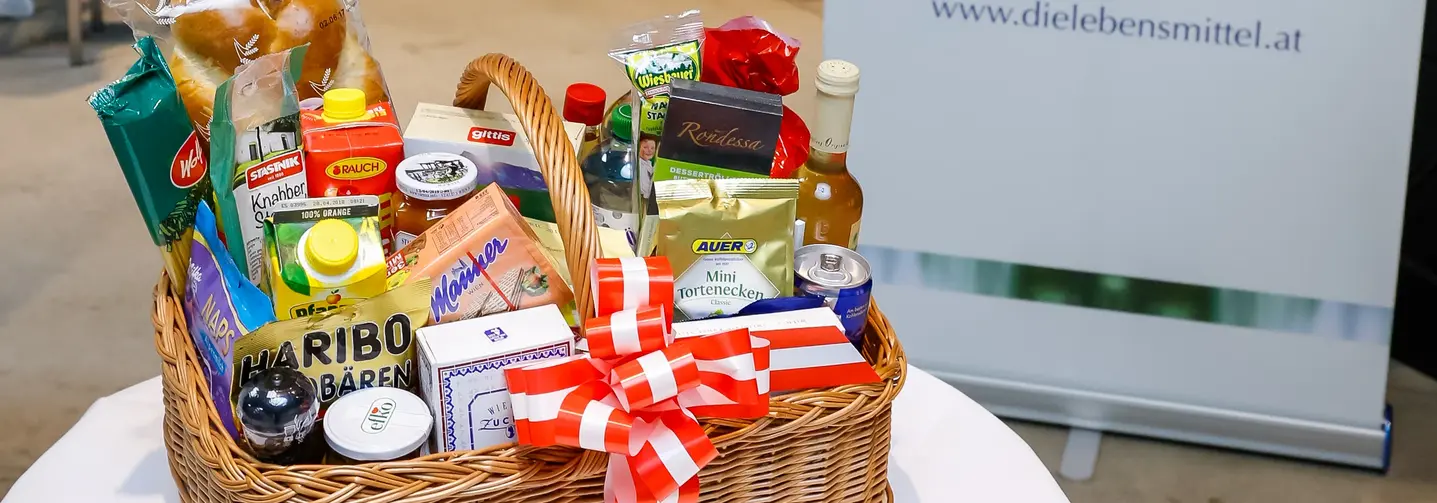 Korb mit österreichischen Marken-Lebensmitteln – von Getränken über Gewürze und Wurstwaren bis zu Süßigkeiten.