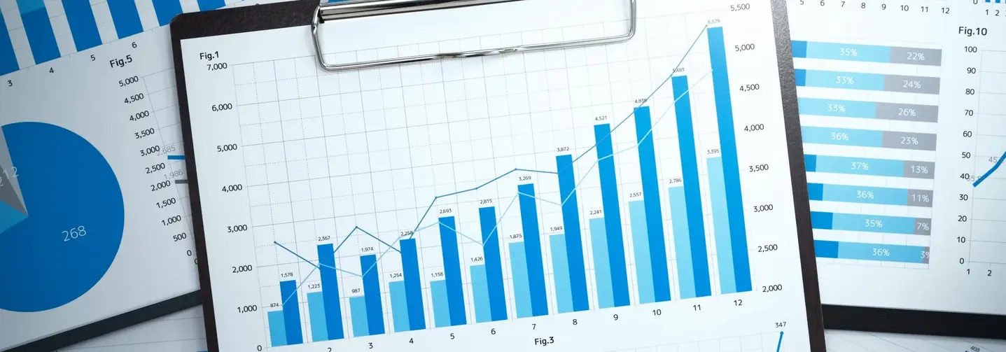 Weiße Papierblätter mit Diagrammen und Statistiken in Blautönen auf schwarzen Klemmbrettern