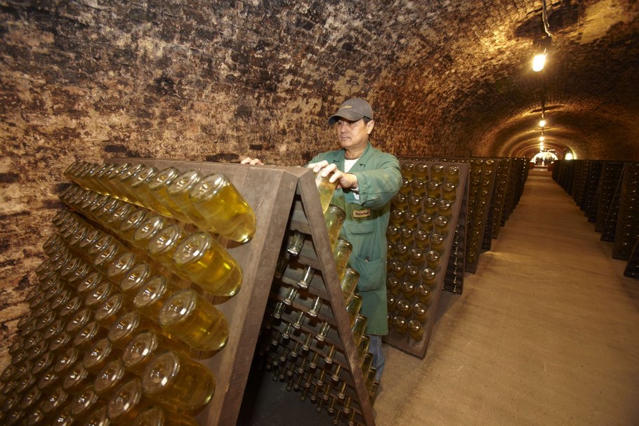 Am Rüttelpult: Nach der Reifung auf der Hefe wird jede Flasche in exakten Intervallen gedreht und etwas steiler gestellt. So sammelt sich die Hefe Schritt für Schritt im Flaschenhals.