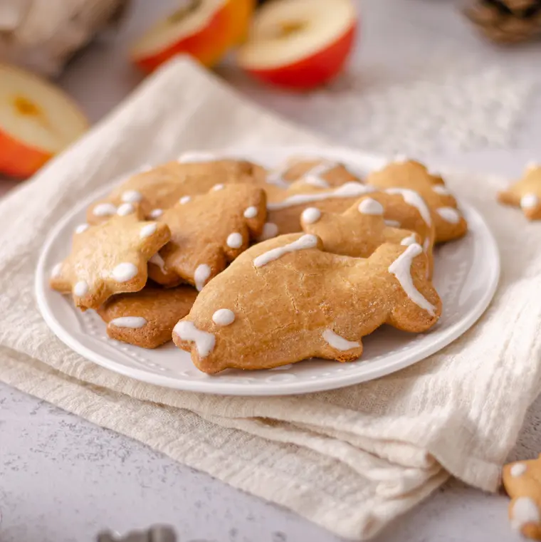 Lebkuchenkeks in Fischform auf einem weißen Teller mit weiteren Lebkuchenkeksen.