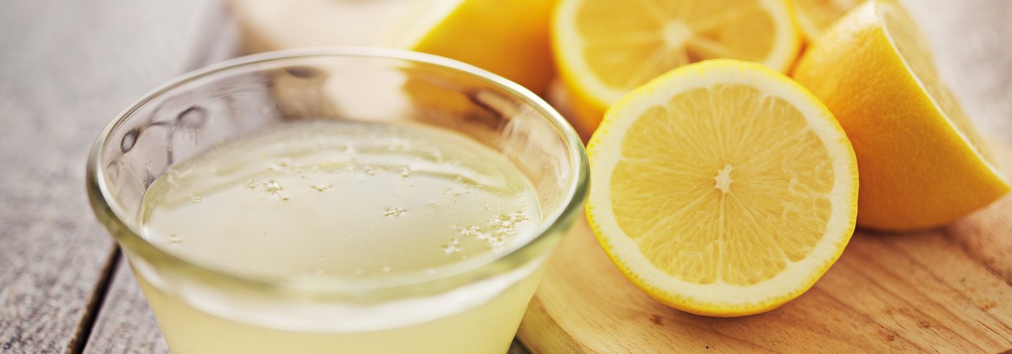 Zitronen und Zitronensaft auf einem Tisch – diese Früchte enthalten von Natur aus Citronen- und Ascorbinsäure.