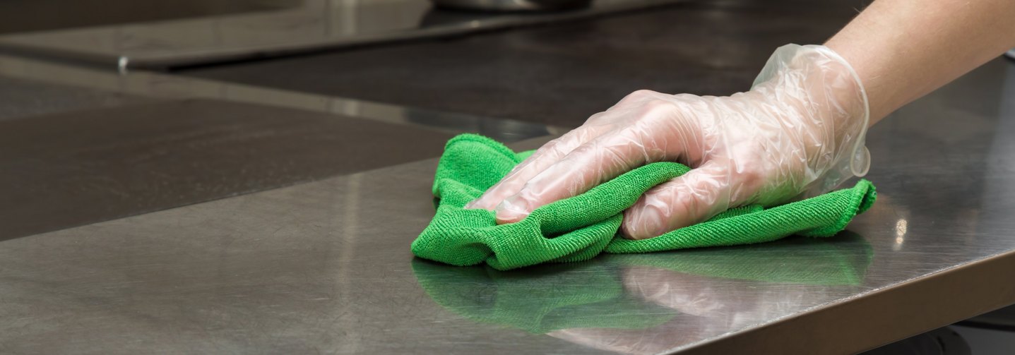 Hygiene in der Lebensmittelindustrie: Eine Person reinigt eine Arbeitsfläche.