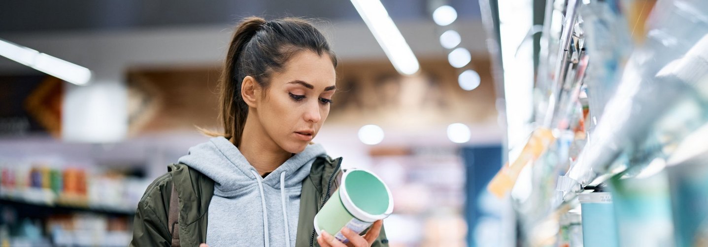 Eine Frau im Supermarkt liest ein Lebensmitteletikett: Stärker verarbeitete Lebensmittel werden oft kritisch hinterfragt.
