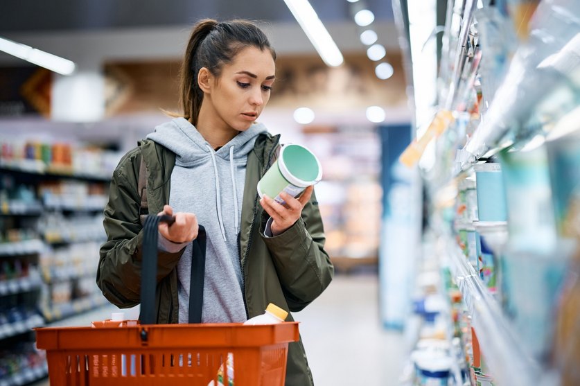 Eine Frau im Supermarkt liest ein Lebensmitteletikett: Stärker verarbeitete Lebensmittel werden oft kritisch hinterfragt.