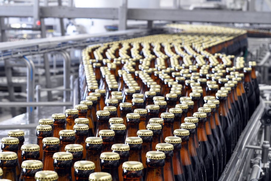 Bierflaschen auf einem Förderband: Bei der Herstellung von alkoholfreiem Bier kommen verschiedene Verfahren zum Einsatz.