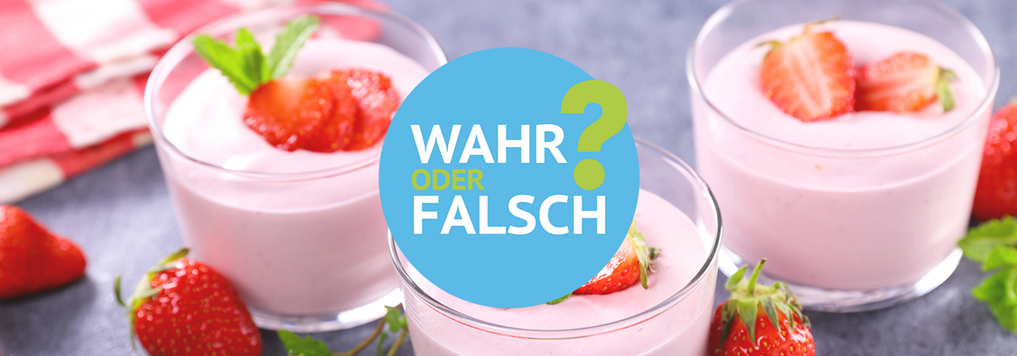 Drei Gläser gefüllt mit Erdbeerjoghurt auf einer grauen Steinplatte, garniert mit frischen Erdbeeren.