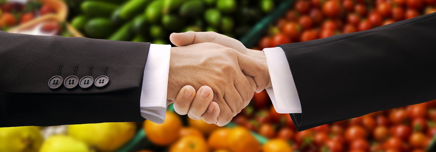 Handschlag vor Lebensmittelregal: Die österreichische Lebensmittelindustrie versorgt unser Land mit Lebensmitteln.