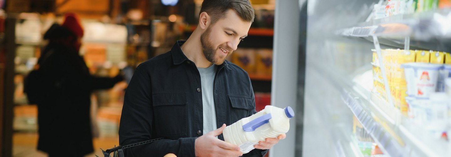 Mann wirft einen Blick auf eine Milchverpackung: Rund um die Kennzeichnung von Lebensmitteln gibt es viele Mythen.