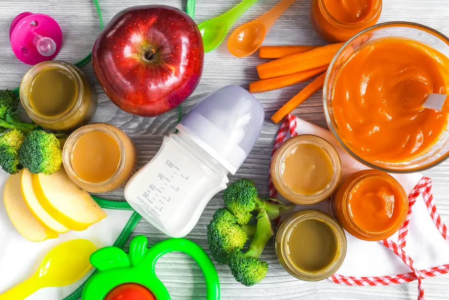 Gläser mit Babybrei, Fläschchen mit Milchnahrung und Obst auf einem Tisch: Das Angebot an Babynahrung ist breit gefächert. Foto: 279photo / iStock